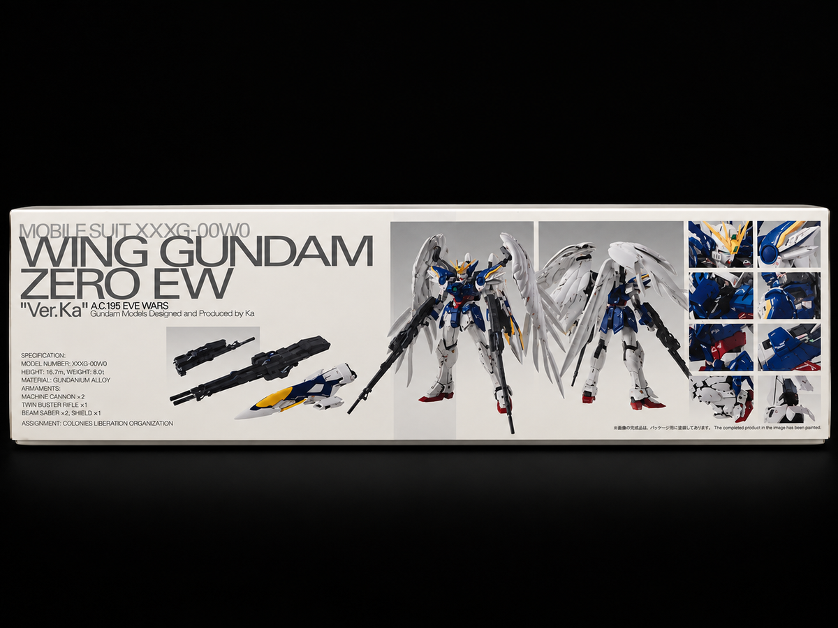 Box packaging for a Gundam model kit, featuring large text reading 'MOBILE-SUIT XXG-00/MO WING GUNDAM ZERO EW' and artwork of a white, blue, and red winged mecha with weapon illustrations, photographed against a black background.