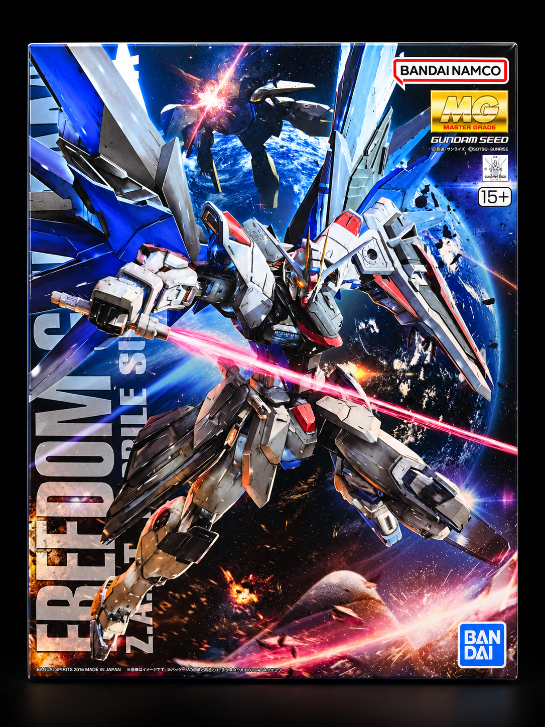 Box art for a Bandai Namco MG Gundam Seed Freedom Seed mobile suit model kit, featuring a detailed sci-fi mecha in space with a red laser beam and Earth in the background.