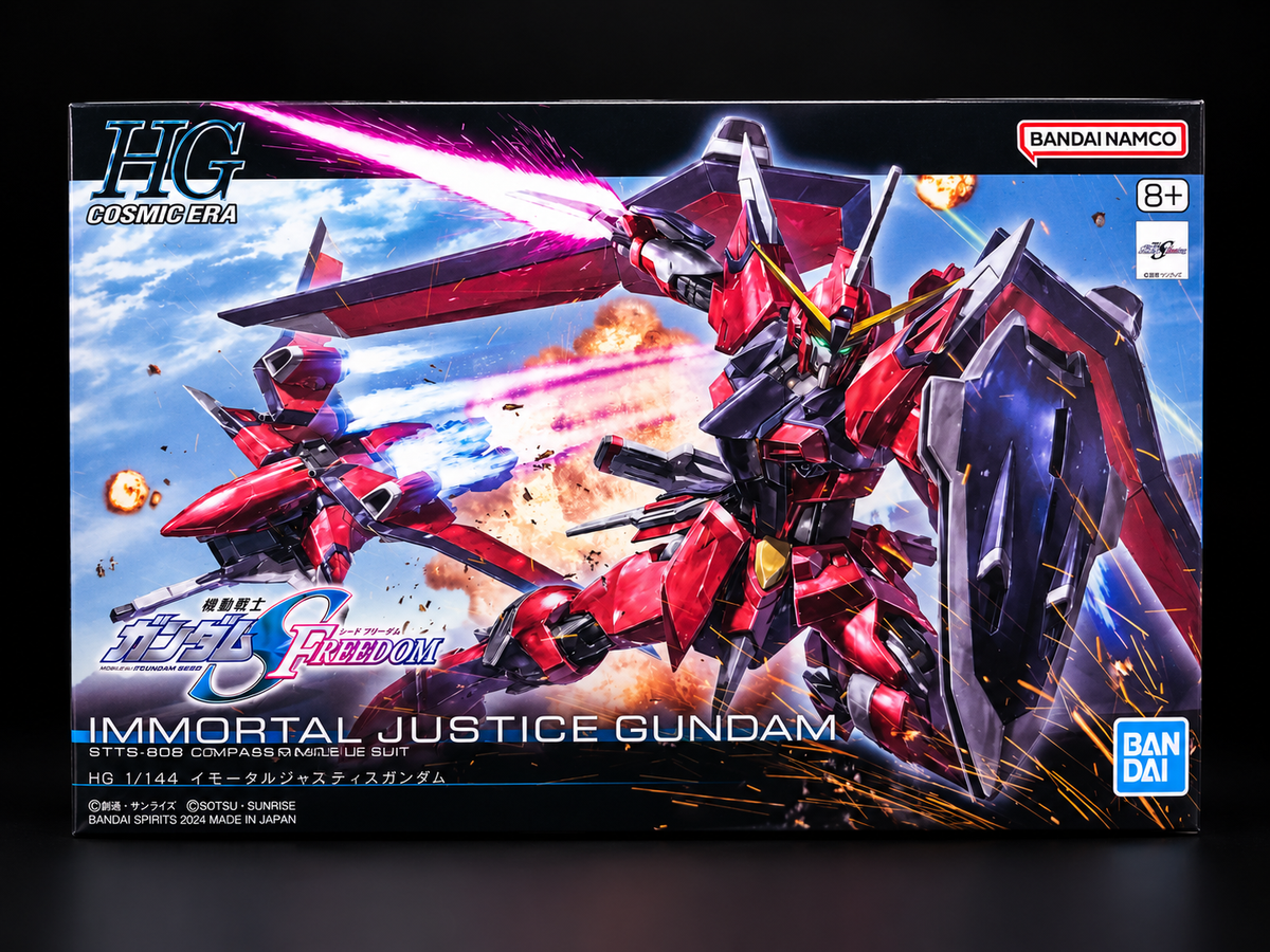 Bandai Namco HG Cosmebota G-Force Free Freedom Immortal Justice Gundam 1/14 scale model kit box, featuring a red and black mecha design with a pink beam saber against a blue sky and explosions.